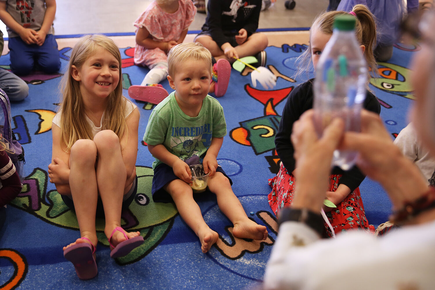 Kids laugh and watch in surprise as Mary Rhoads squeezes